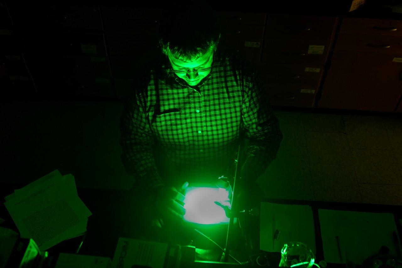 Dr. 乔·弗加尔站在一盏明亮的绿光前，这是他博天堂官方网站光与物质相互作用的实验的一部分, BGSU的博士.D. 光化学科学